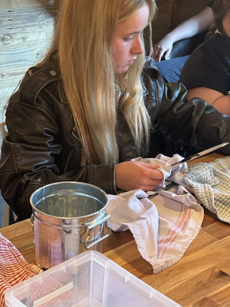 Young teenager, white skin and bond hair, polishing cutlery.
